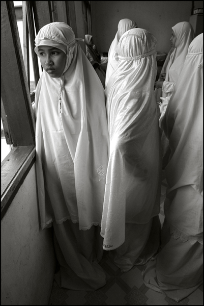 A girl stares out through a window just before the midday prayer at an orphanage in Banda Aceh Indonesia