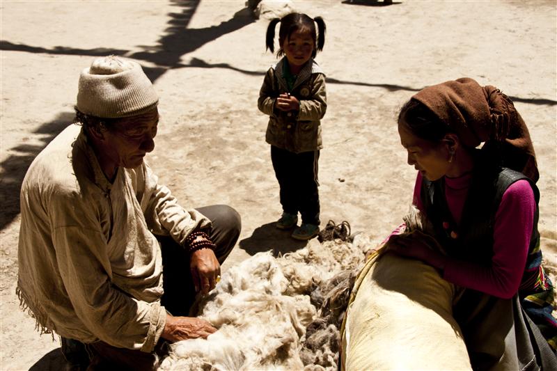 A young girl watches her family member work with school inside the house in Lo Manthang