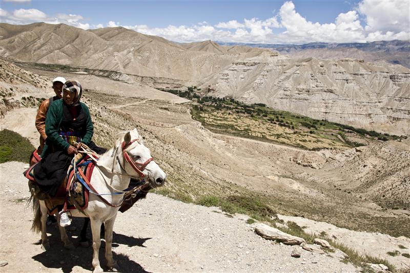 Local Loba women rides a horse to visit the next village.