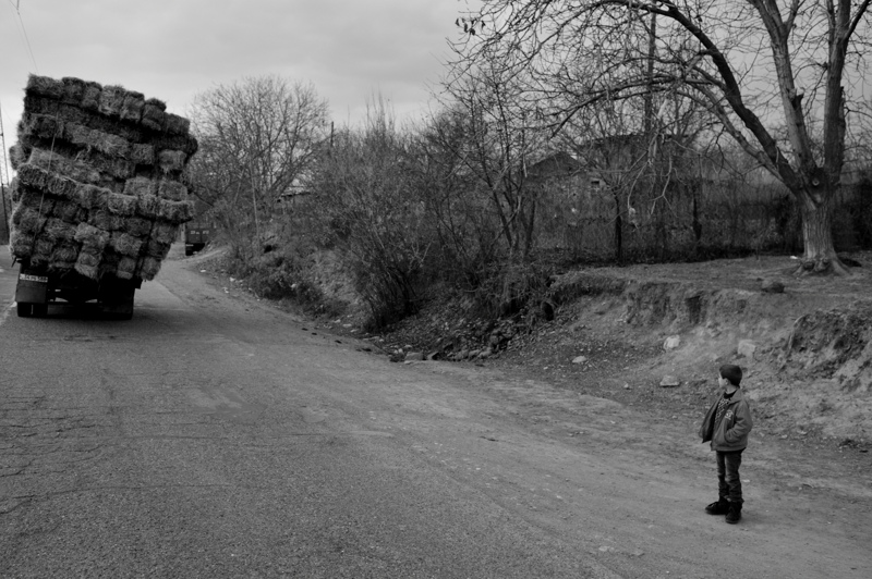 Hay truck passes a boy on the roadside north of Agarak