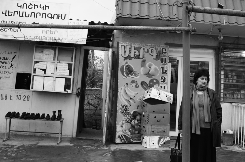 Waiting for a bus, a woman not certain of the the photographer in the passing car.