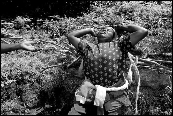 A woman is being helped to unload her firewood to have a rest.