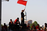 Red shirt protester waves a red flag at the Silom barricade