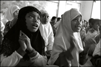 Two orphan girls clapping their hands as they sing a song in the morning class