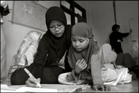 A student of the Fajar Hidayah organization helps a young girl with writing some English at an orphanage in Banda Aceh Indonesia