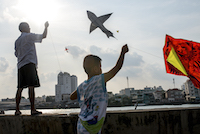 Residents of a fisherman's village fly kites
