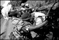 A woman is being helped to unload her firewood to have a rest.